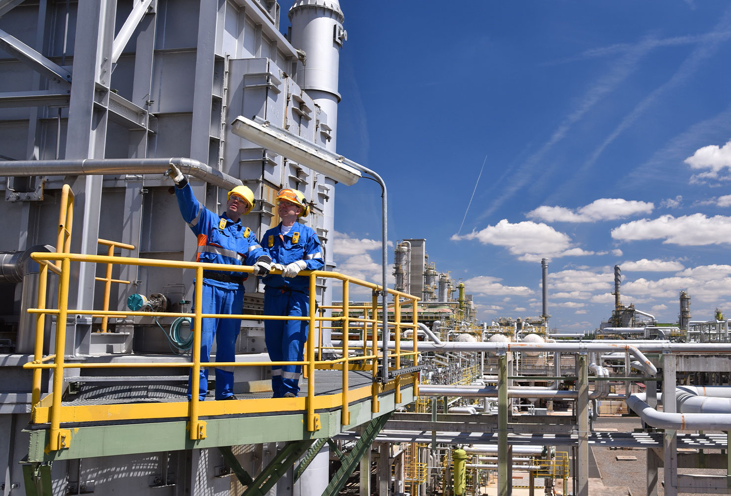 group of industrial workers in a refinery - oil processing equipment and machinery