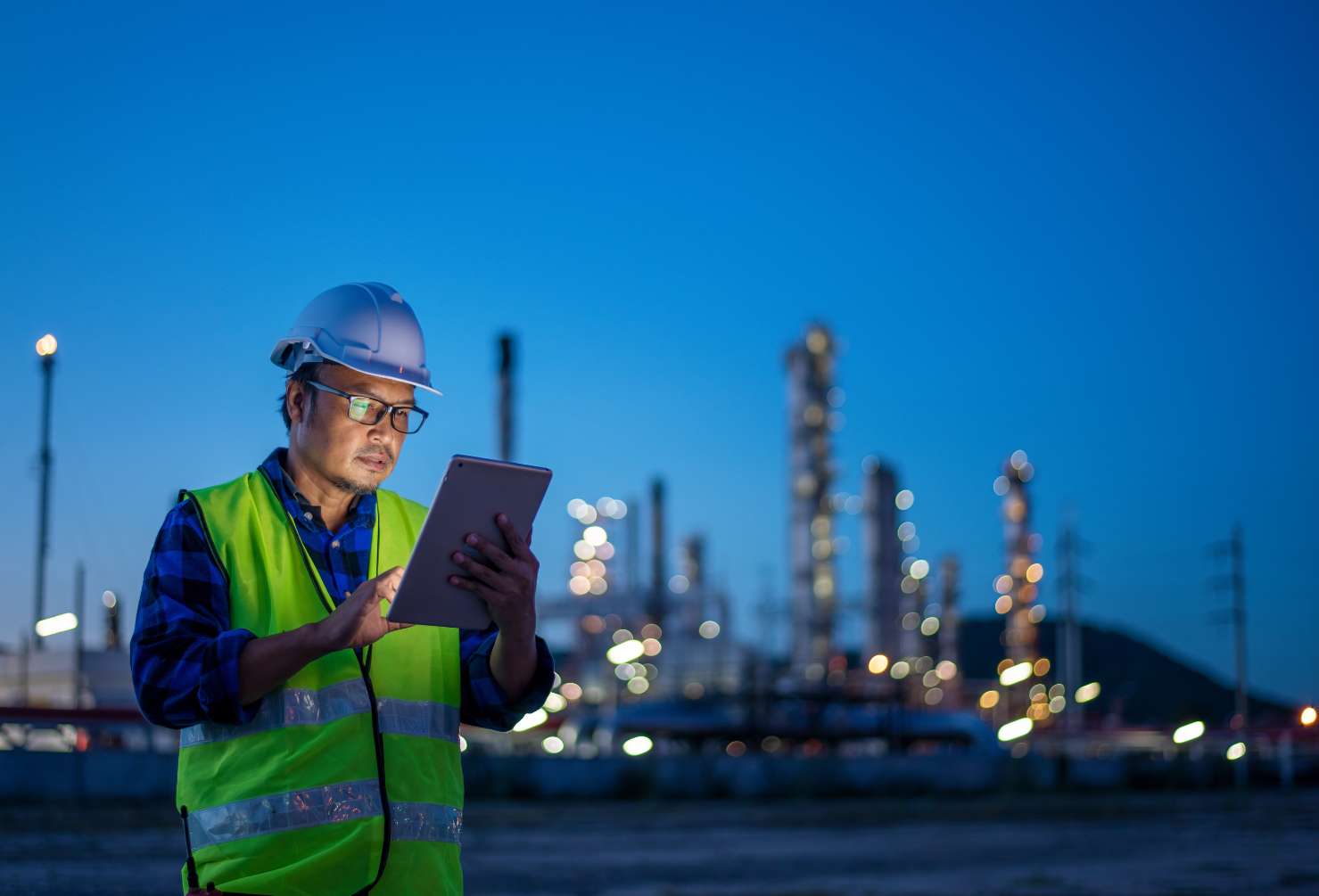 Should I Stay or Should I Go? How to Know When It’s Time to Move Projects in Oil & Gas Engineer wearing safety uniform and helmet looking detail tablet on hand with oil refinery factory at night time background