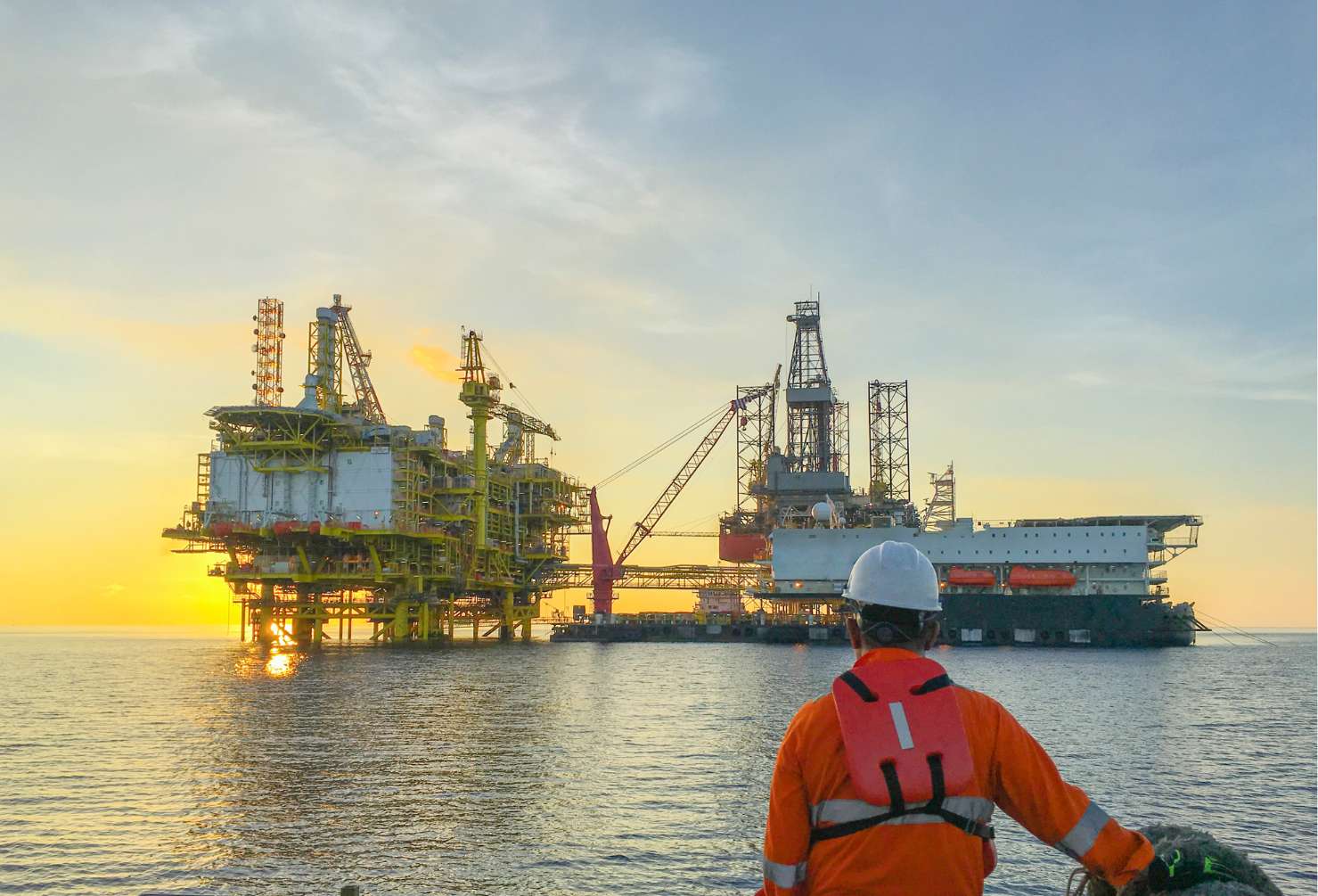 Enxgy-Blog-Wind-Project-Cancellation-For-Oil-Gas-Talent-2025 Oil and gas industry. Marine crew standing on supply vessel looking oil and gas platform during sunrise.