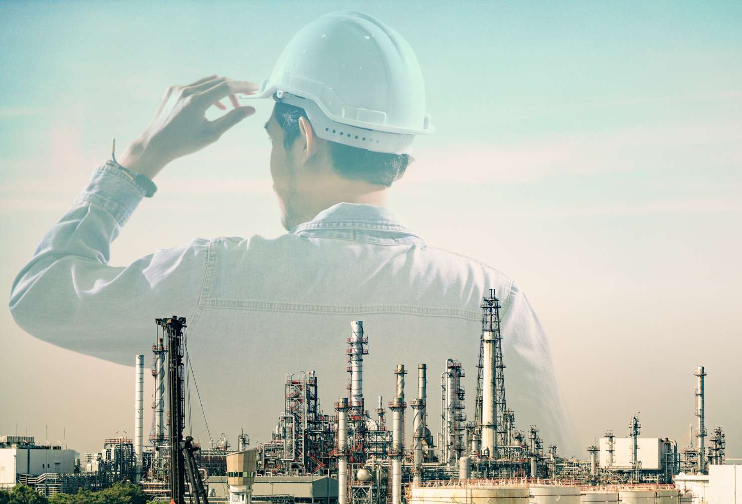 Double exposure of behind engineer wearing helmet safety with Blurred Oil refinery plant as a background. Oil and gas business company, Human resources and recruitment for energy industrial.