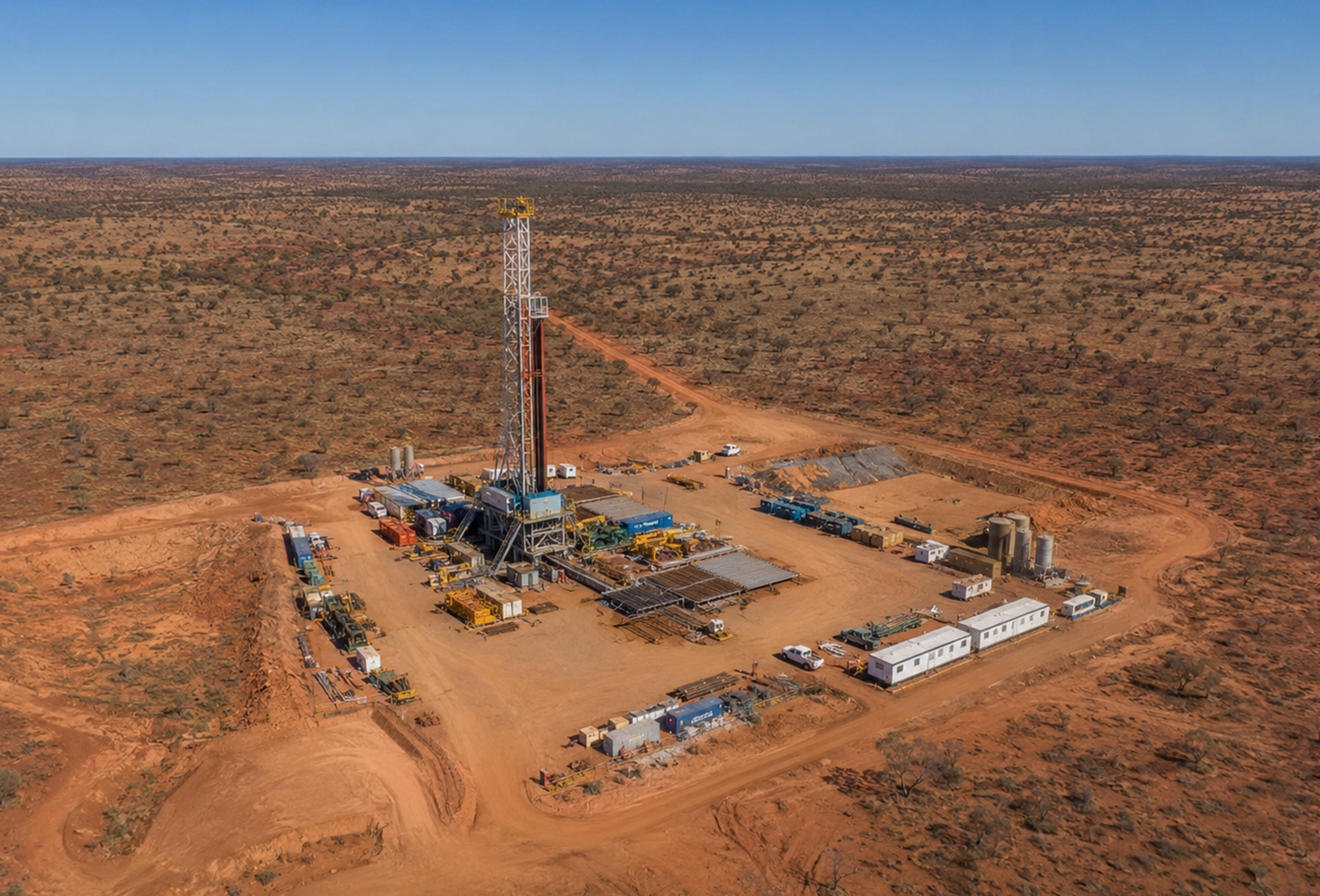 Aerial view of an active onshore oil and gas exploration drilling site in outback Australia, a tall drilling rig surrounded by exploration equipment and vehicles, wide open landscape stretching to the horizon